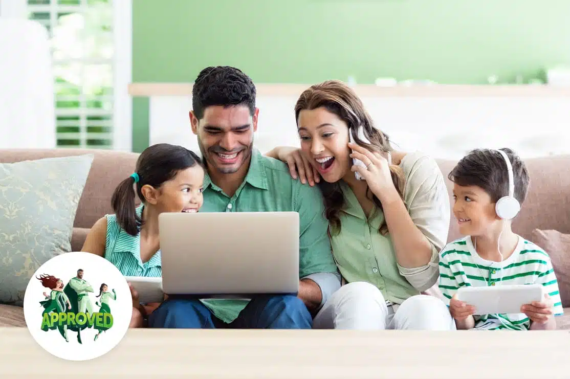 Happy family of four sitting on a couch, using a laptop together, representing the benefits of home equity loans for financial flexibility.